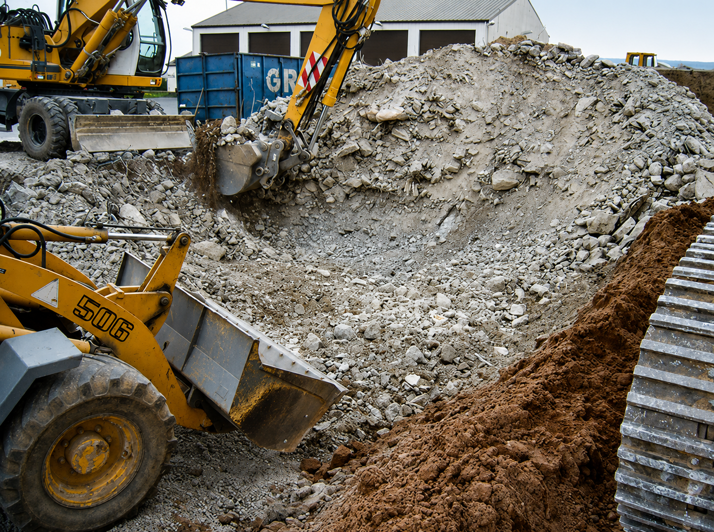 Radlader und Bagger beim Sortieren und Verladen von Bauschutt für das Recycling