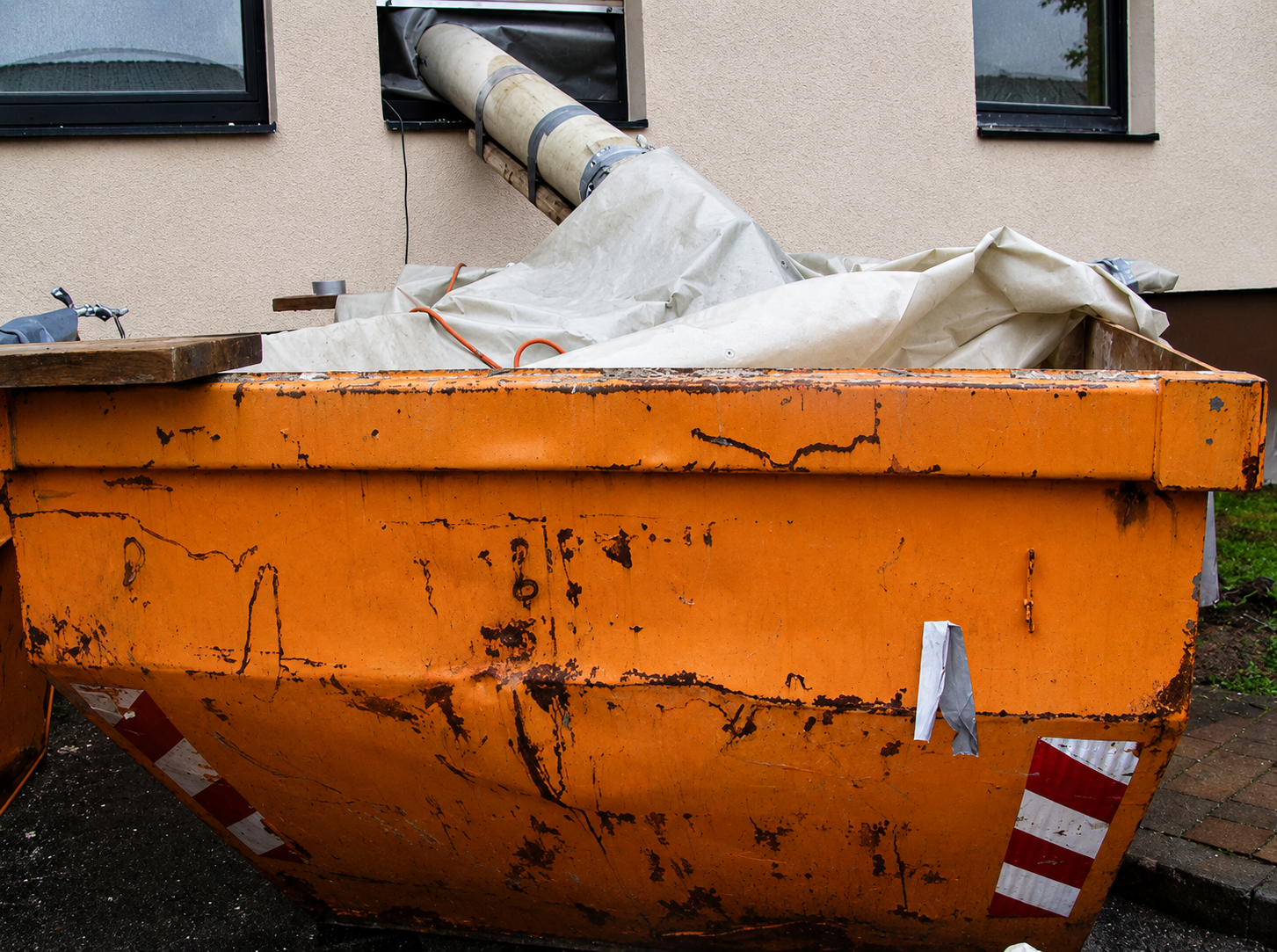 Verbringung von Schutt mittels eingehauster Schuttrutsche und Container vor Gebäude