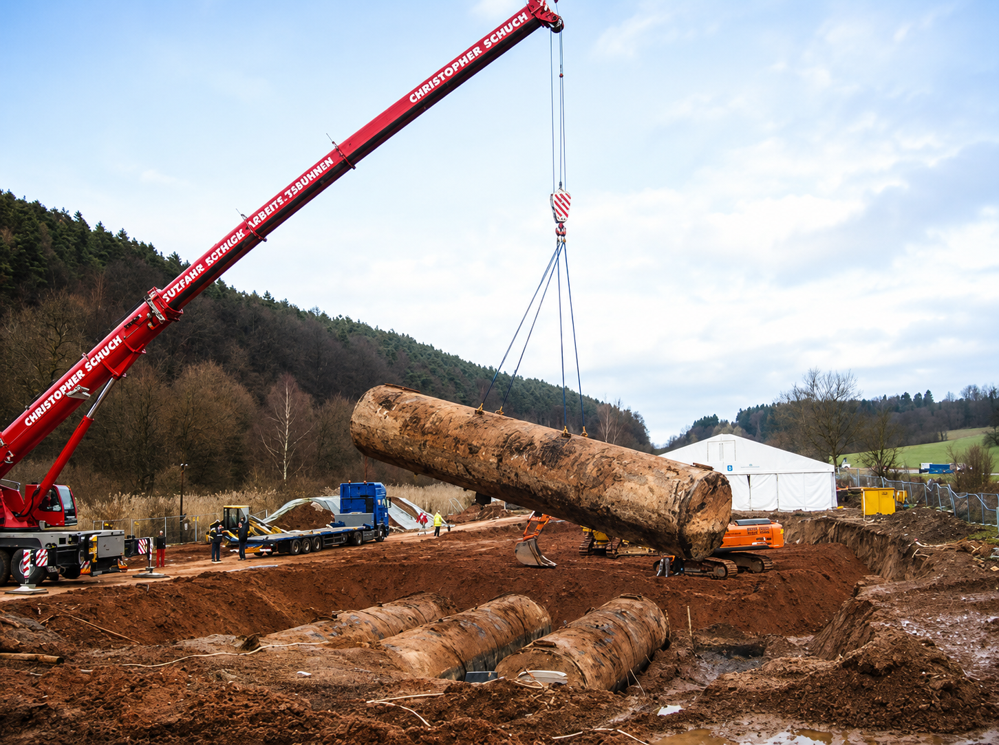 Sanierung eines Tanklagers – großer Heizöltank wird mit einem Mobilkran aus dem Erdreich gehoben